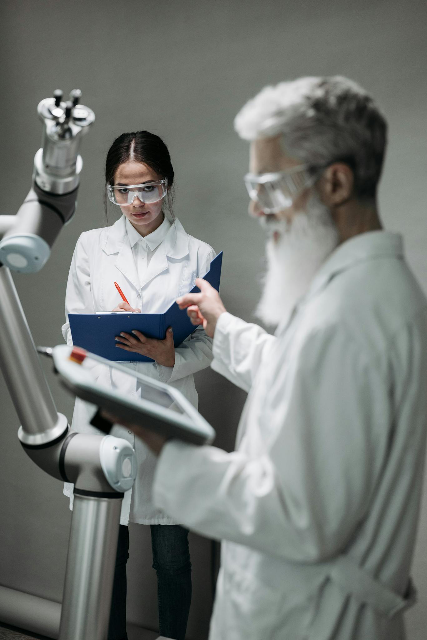 Researchers in lab coats interacting with advanced robotic arm technology.