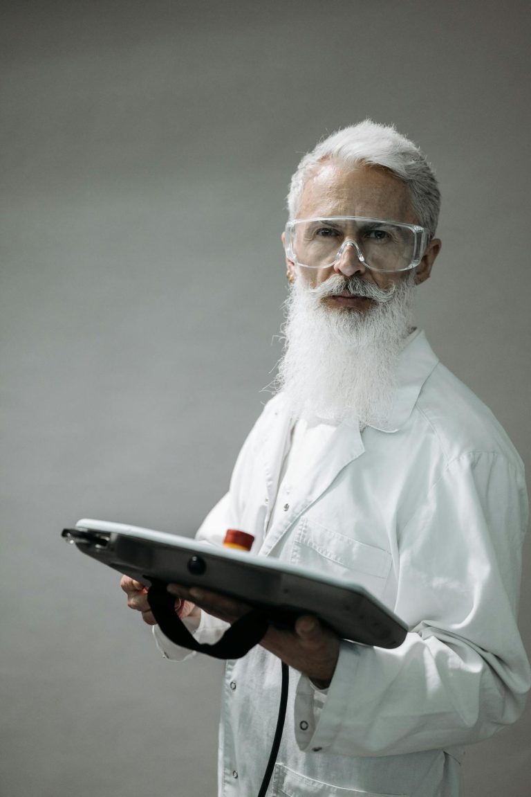 Senior male scientist in lab coat using a control tablet in a lab environment.